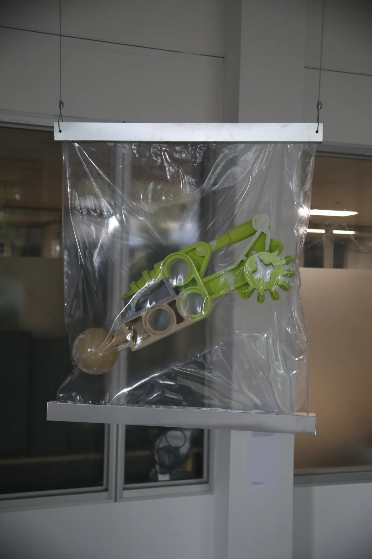 One of the sculptures of the work Residual Protodermis hanging from the ceiling in a vacuum sealed bag with aluminum details.